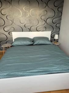 a bed with a green comforter and two tables at Apartments Spačilova nearly center in Komárov