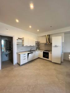 a kitchen with white cabinets and a white refrigerator at Ascensore per la spiaggia in Cirella