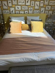 a bed with yellow and white pillows on it at L’Aubépine in Saint-Gervais-la-Forêt