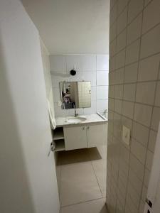 uma casa de banho branca com um lavatório e um espelho em Carneiros Tamandare Apart Hotel Marinas em Tamandaré