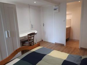 1 dormitorio con cama, escritorio y mesa en Bel appartement rez-de-jardin, en Saint-Genest-Malifaux