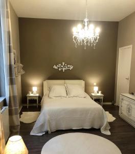 um quarto com uma cama branca e um lustre em Appartement Périgueux historique em Périgueux