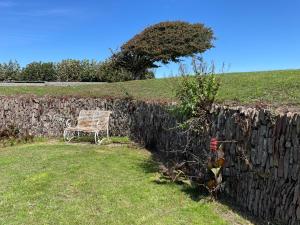 a wooden bench sitting next to a stone wall at The Downs, Thurlestone, South Devon, close to several beaches in Kingsbridge