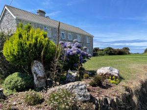 a garden in front of a house with purple flowers at The Downs, Thurlestone, South Devon, close to several beaches in Kingsbridge