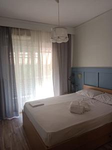 una camera da letto con un grande letto bianco e una finestra di LOVELY APARTMENT a PalaiónTsiflíkion