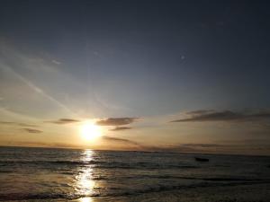 a sunset on the beach with a boat in the water at Beach House in Playa Junquillal