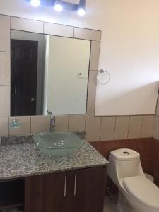 a bathroom with a sink and a toilet and a mirror at Beach House in Playa Junquillal