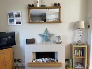 a living room with a white fireplace with a mirror at The Downs, Thurlestone, South Devon, close to several beaches in Kingsbridge