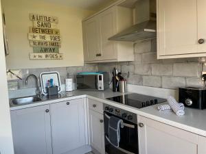 a kitchen with white cabinets and a sink and a stove at The Downs, Thurlestone, South Devon, close to several beaches in Kingsbridge