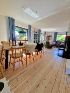 a living room with a table and a dog sitting on chairs at Det Gamle Garnbinderi, ved Møns bedste strand. in Borre