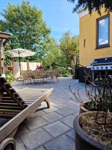 a patio with a table and chairs and an umbrella at Det Gamle Garnbinderi, ved Møns bedste strand. in Borre