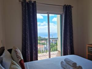 a bedroom with a window with a view of a balcony at Villa&Damata in Água de Pena