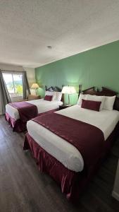 2 Betten in einem Hotelzimmer mit grünen Wänden in der Unterkunft Colonial Inn Franklin in Franklin