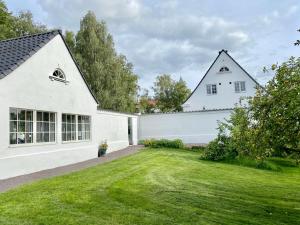 Sösdala的住宿－Exklusivt gästhus på anrik prästgård，一座带草地庭院的大型白色房屋