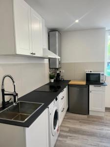 uma cozinha com armários brancos, um lavatório e uma máquina de lavar louça em Accès Mer - Netflix - Fibre - T2 IODELYS em Larmor-Baden
