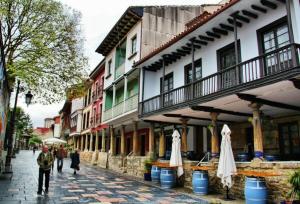 a group of people walking down a street with buildings at Puerta la Villa in Avilés
