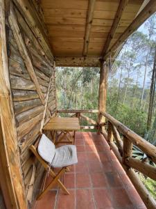 un porche de una cabaña de madera con un banco y una silla en The Hideout- A Cabin in Nature; 25 min from Cuenca, en Cuenca