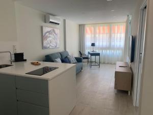 a kitchen and living room with a blue couch at RENOVADO APARTAMENTO 1º LINEA DE MAR in San Agustin