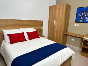 1 dormitorio con 1 cama grande y 2 almohadas rojas en Westlands Tower - Ghana Villas, en Accra