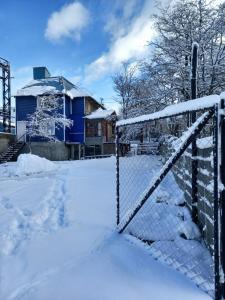 une clôture recouverte de neige devant une maison dans l'établissement hostel comunidad Ushuaia, à Ushuaia