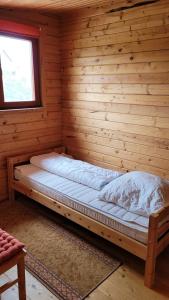 Ce lit se trouve dans une cabane en rondins dotée d'une fenêtre. dans l'établissement Ferienhaus Bliev-Hee Nr 4, à Klink