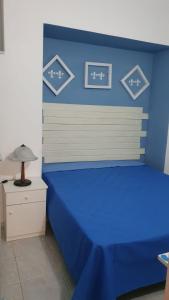 a bedroom with a blue bed with a lamp on a dresser at La Dimora del Frappato di Tenute Senia in Chiaramonte Gulfi