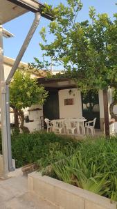 um pátio com cadeiras brancas e uma mesa em frente a uma casa em La Dimora del Frappato di Tenute Senia em Chiaramonte Gulfi