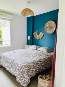 een slaapkamer met een bed met een blauwe muur bij Appartement cosy in Sarlat-la-Canéda