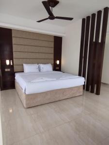 a bedroom with a large bed with a ceiling fan at White Park Hotel & Suites in Chittagong