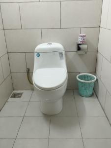 a bathroom with a toilet in a white tiled room at White Park Hotel & Suites in Chittagong