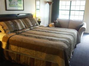 a bedroom with a bed and a couch and windows at Deerwood Inn & Madison Campground in Madison
