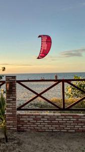 a kite is flying over a fence at the beach at BEACH HOUSE - Loggia Suite 3 - com cozinha - na praia - BEACHFRONT in Barra Grande +47 photos