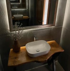 een badkamer met een witte wastafel en een spiegel bij Club12 pool house in Čačak