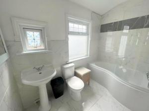 a white bathroom with a sink and a toilet and a tub at 3-bedroom house - Thornton Heath in Thornton Heath
