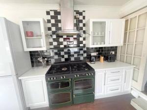 a kitchen with a green stove and white cabinets at 3-bedroom house - Thornton Heath in Thornton Heath