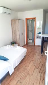 een slaapkamer met een wit bed en een houten vloer bij Studio apartman Kiara in Bol