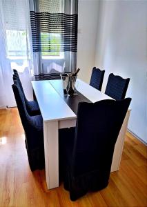 - une table à manger blanche avec des chaises noires et une table blanche dans l'établissement Stan Na Dan / Stan Na Izdavanje, à Paraćin