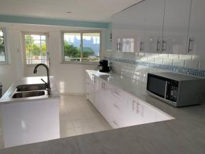 a white kitchen with a sink and a microwave at BidaBreezes Villa Great Location in Palm-Eagle Beach