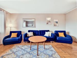 salon z niebieskimi kanapami i stołem w obiekcie CLASSY APARTMENTS - Gdynia - Słoneczny w mieście Gdynia