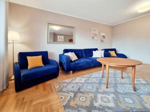 salon z niebieskimi kanapami i stołem w obiekcie CLASSY APARTMENTS - Gdynia - Słoneczny w mieście Gdynia