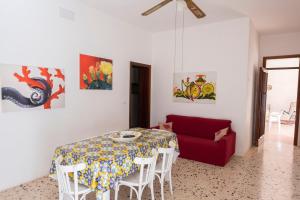 ein Esszimmer mit einem Tisch und einem roten Sofa in der Unterkunft Casa Lisa a due passi dal mare con ampio giardino in San Vito lo Capo