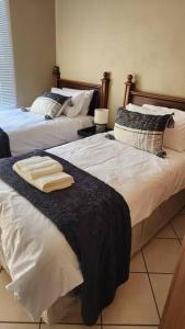 two beds in a bedroom with two towels on them at @LloydsII in Ermelo