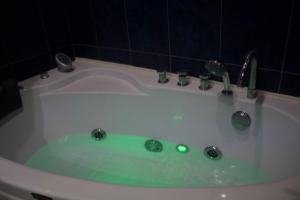 a bath tub with green water in a bathroom at Welhome to a city centre Cozy and Comfy For leisure and Work No go through No other guests Just one host who you can ghost in Tbilisi City +64 photos