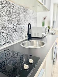 a kitchen with a sink and a black and white tiles at ApartSur® in Bormujos