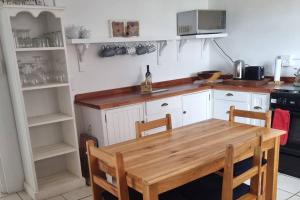 a kitchen with a wooden table and a stove at Hysie oppie see in Jongensfontein