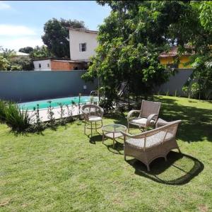 a yard with chairs and a table and a swimming pool at CASA TROPICANA - ITAÚNAS Centro in Itaúnas