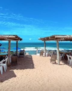 a beach with chairs and tables and the ocean at CASA TROPICANA - ITAÚNAS Centro in Itaúnas