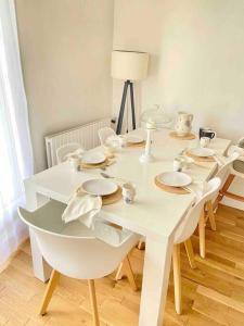 a white dining room table with plates and bowls on it at Appartement avec deux balcons in Magny-les-Hameaux