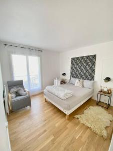 a white room with a bed and a chair at Appartement avec deux balcons in Magny-les-Hameaux