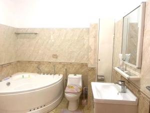 a bathroom with a tub and a toilet and a sink at Hôtel Sky blue Mada in Alasora